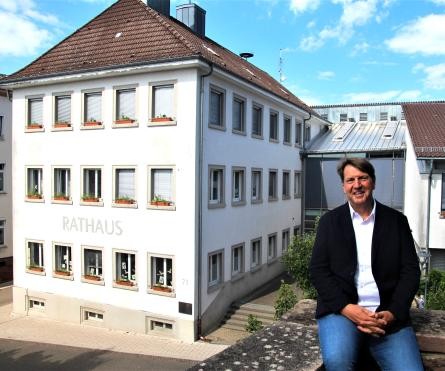 Bürgermeister Markus Bechler auf Mauer sitzend vor dem Rathaus Malsch